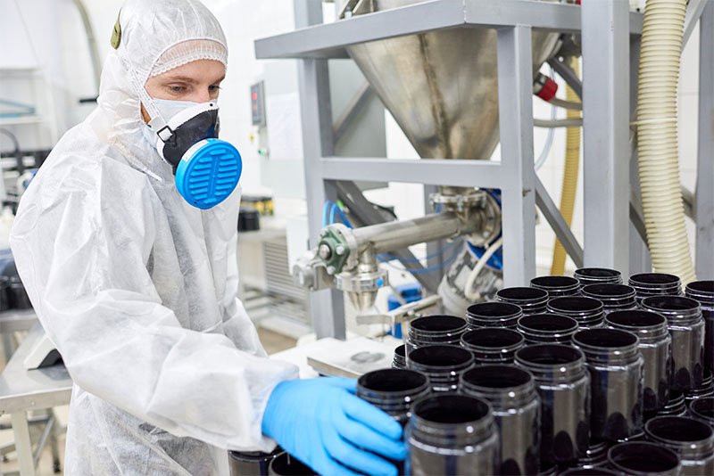 Factory employee taking plastic jar from manufacturing order of sports supplement, creatine, hmb, bcaa, amino acid or powdered vitamin. Sports nutrition production
